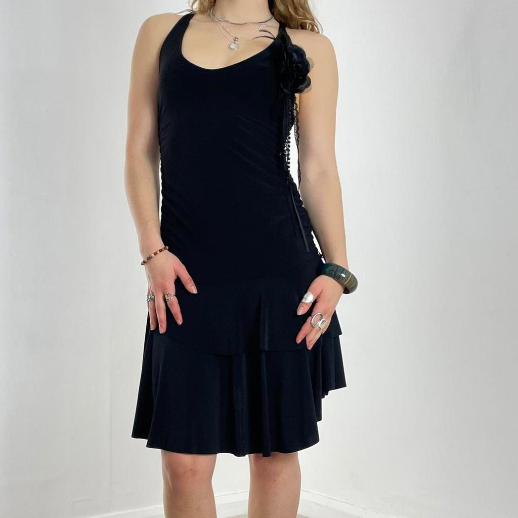 Vintage black flared dress with a low cut and cross back, with a flower pin and tired skirt