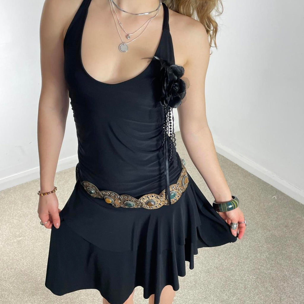 Vintage black flared dress with a low cut and cross back, with a flower pin and tired skirt