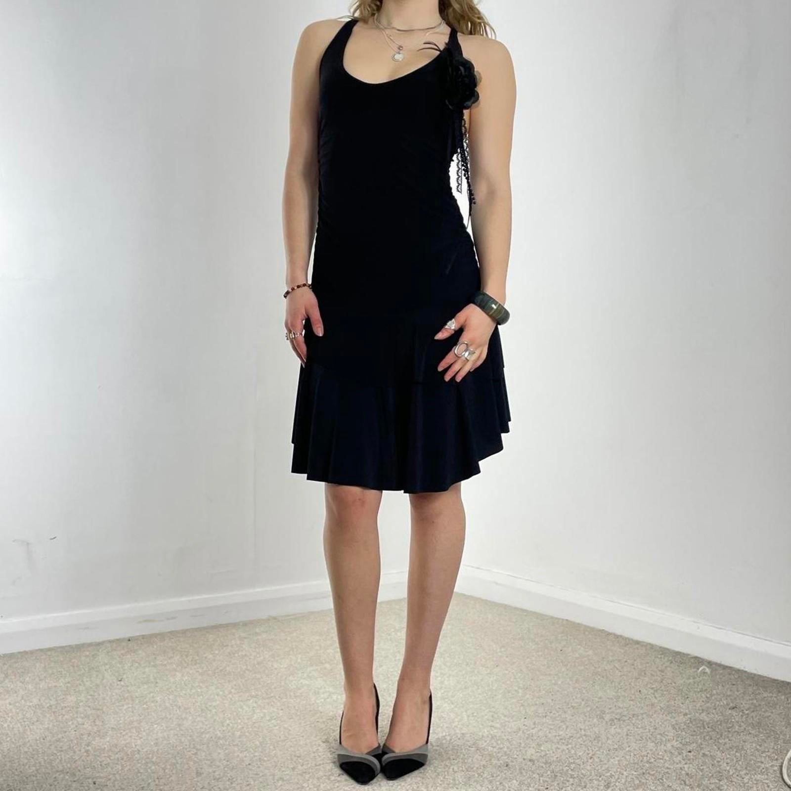 Vintage black flared dress with a low cut and cross back, with a flower pin and tired skirt