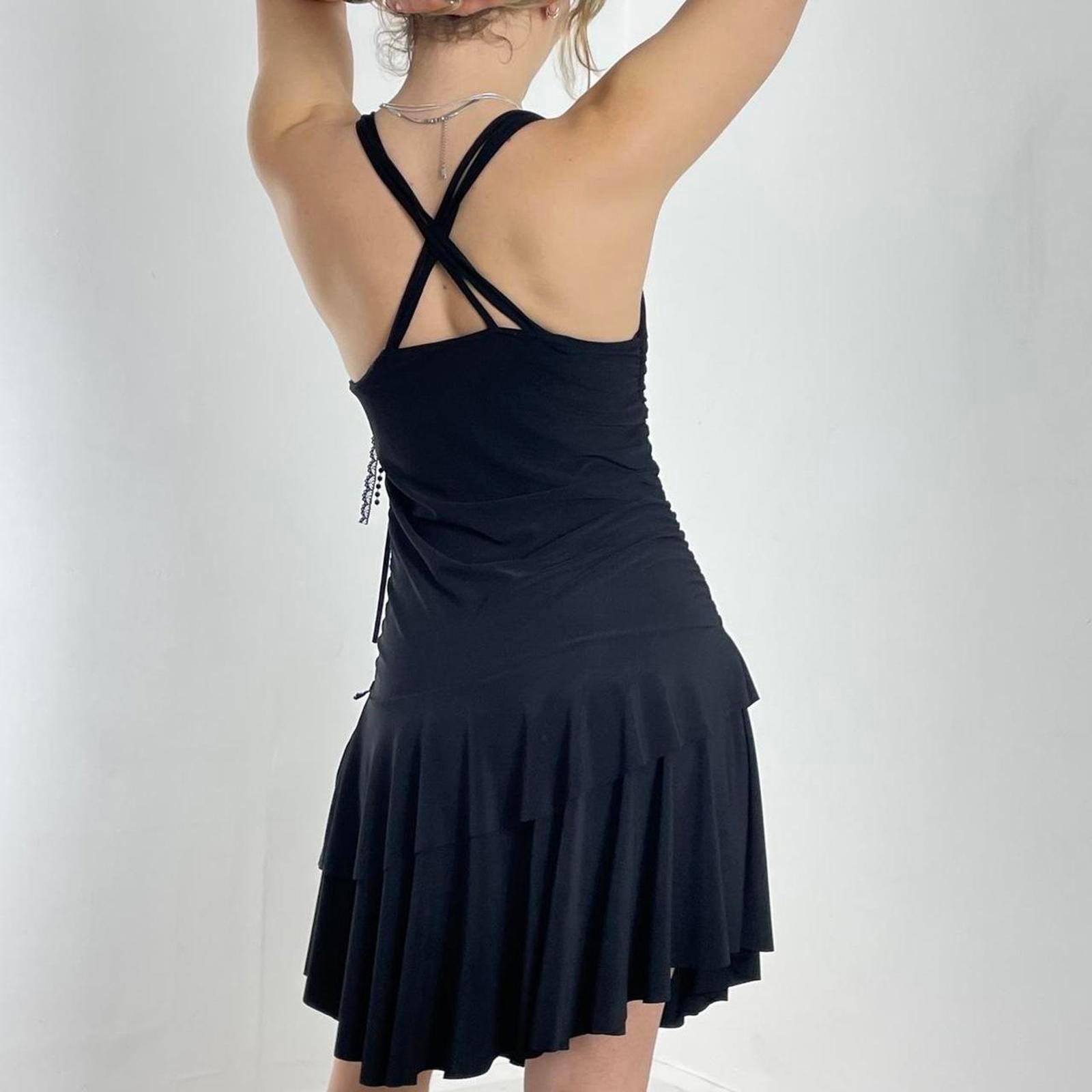 Vintage black flared dress with a low cut and cross back, with a flower pin and tired skirt