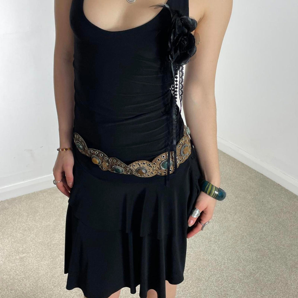 Vintage black flared dress with a low cut and cross back, with a flower pin and tired skirt